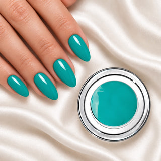 Nageldesign in Türkis Blau neben einem offenen Farbgel-Tiegel auf weißem Stoff