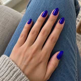 Nageldesign in Royal Blau – Hand mit lackierten Nägeln auf blauem Jeansstoff