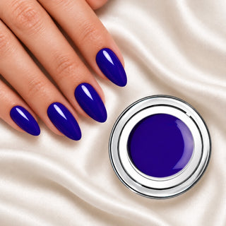 Nageldesign in Royal Blau neben einem offenen Farbgel-Tiegel auf weißem Stoff