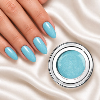 Nageldesign in Glimmer Baby Blau neben einem offenen Farbgel-Tiegel auf weißem Stoff