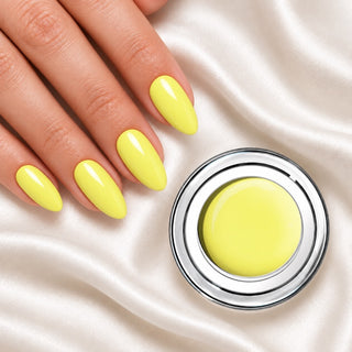 Nageldesign in Pastell Gelb neben einem offenen Farbgel-Tiegel auf weißem Stoff