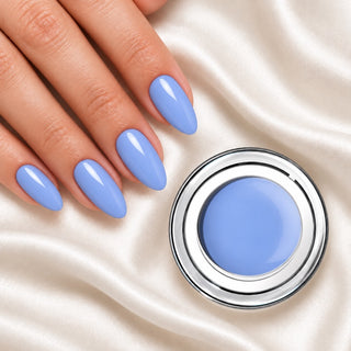 Nageldesign in Puder Blau neben einem offenen Farbgel-Tiegel auf weißem Stoff