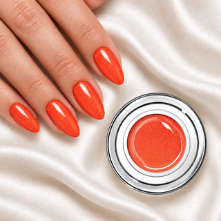 Nageldesign in Glimmer Orange neben einem offenen Farbgel-Tiegel auf weißem Stoff