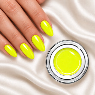 Nageldesign in Metallic Neon Gelb neben einem offenen Farbgel-Tiegel auf weißem Stoff