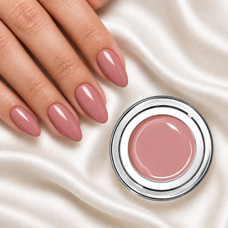 Nageldesign in Creamy Nude Lilac neben einem offenen Farbgel-Tiegel auf weißem Stoff