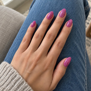 Nageldesign in Disco Pink Lila – Hand mit lackierten Nägeln auf blauem Jeansstoff