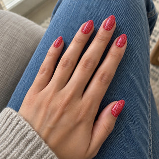 Nageldesign in Disco Rot – Hand mit lackierten Nägeln auf blauem Jeansstoff