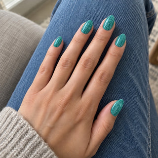 Nageldesign in Disco Grün – Hand mit lackierten Nägeln auf blauem Jeansstoff