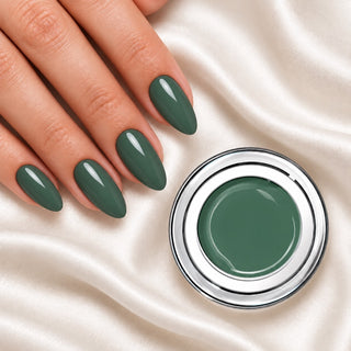 Nageldesign in Nude Türkis neben einem Farbgel-Tiegel auf weißem Stoff