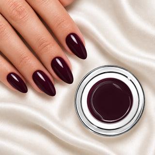 Nageldesign in Dunkles Wein Rot neben einem Farbgel-Tiegel auf weißem Stoff