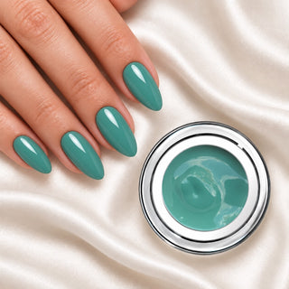 Nageldesign in Sanftes Moos Grün neben einem Farbgel-Tiegel auf weißem Stoff