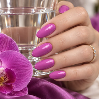 Hand mit fliederfarbenen Nägeln hält ein Wasserglas neben einer violetten Orchidee – Rockstar Nails Gellack 90018.
