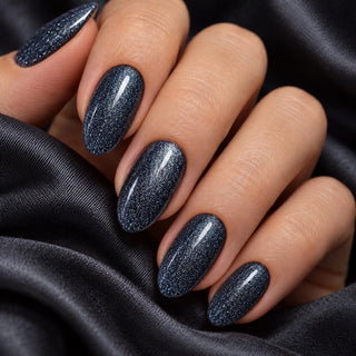 Hand mit glänzenden Nägeln in Galaxy Schwarz auf schwarzem Satin – Rockstar Nails 3in1 UV Gellack 90024.
