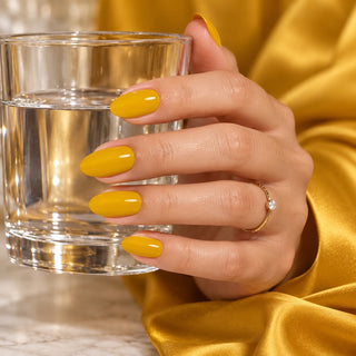 Hand mit senfgelben Nägeln hält eine schwarze Flasche Rockstar Nails 3in1 UV Gellack 90030.