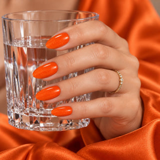 Hand mit Nägeln in Metallic Orient Orange hält ein Wasserglas – Rockstar Nails 3in1 UV Gellack 90134.
