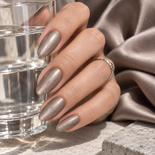 Hand mit Nägeln in Metallic Grau Braun hält ein Wasserglas – Rockstar Nails 3in1 UV Gellack 90149.