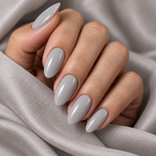 Hand mit glänzenden, mandelförmigen Nägeln in Marmor Grau auf silbergrauem Satin – Rockstar Nails Gellack 90232.