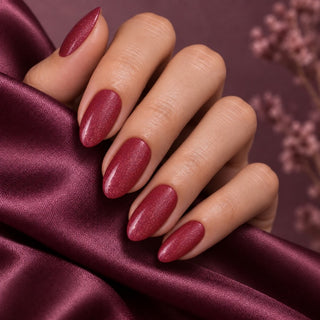Hand mit glänzenden Nägeln in Glitter Violett Rot auf violettem Satin – Rockstar Nails 3in1 UV Gellack 90013.